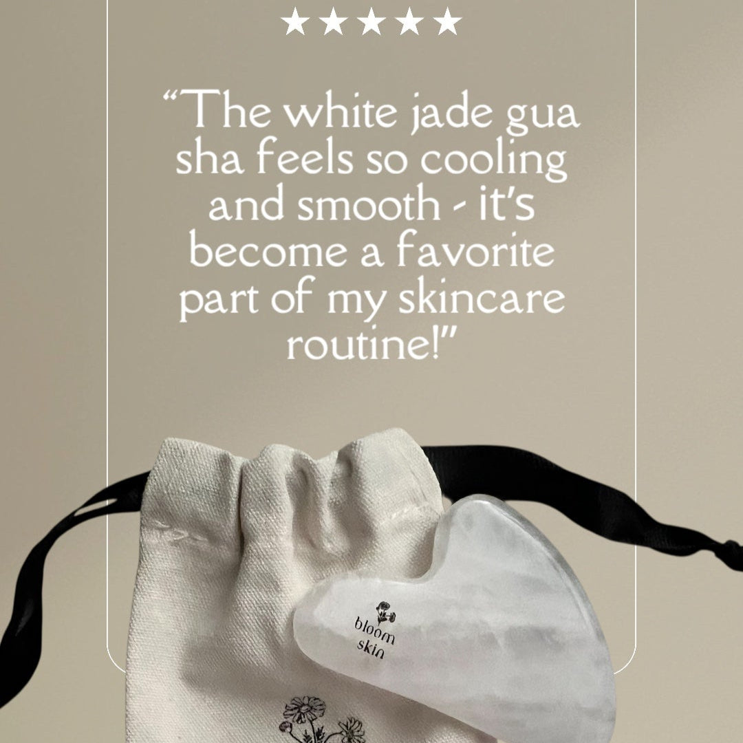 White jade gua sha tool with 'bloom skin' branding and customer review on a beige background
