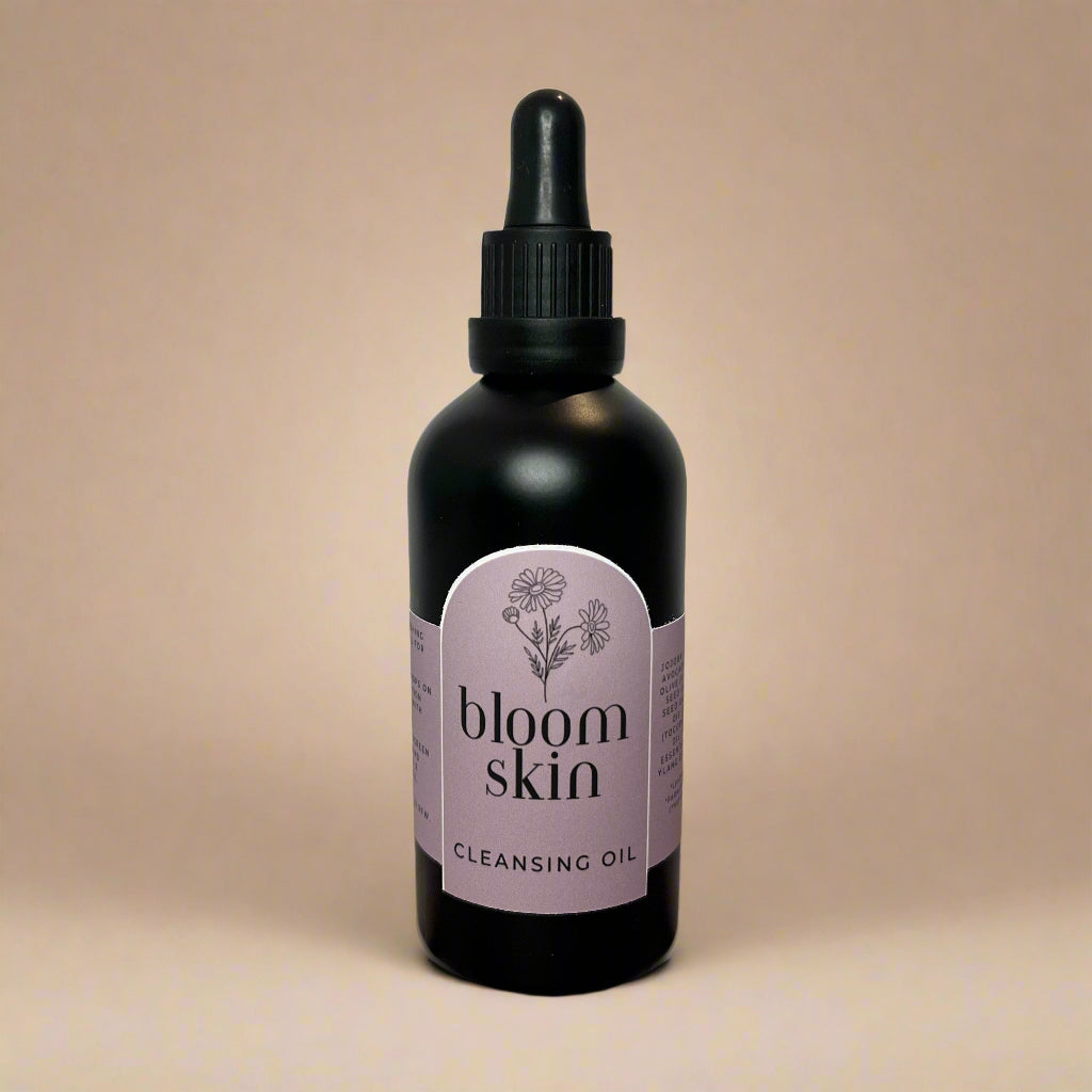 Bottle of 'bloom skin' cleansing oil on a wooden surface with a white background