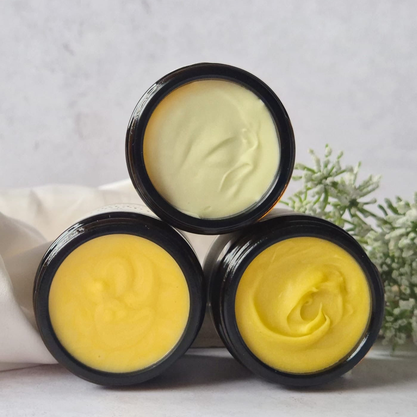 Three black containers with yellow and white substances on a light gray background