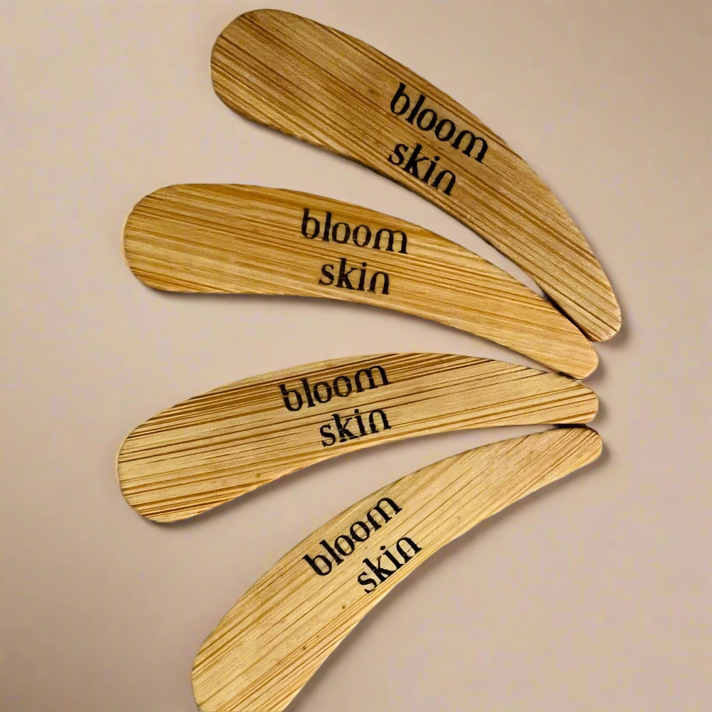 Four wooden stirrers with 'bloom skin' engraving on a wooden surface.