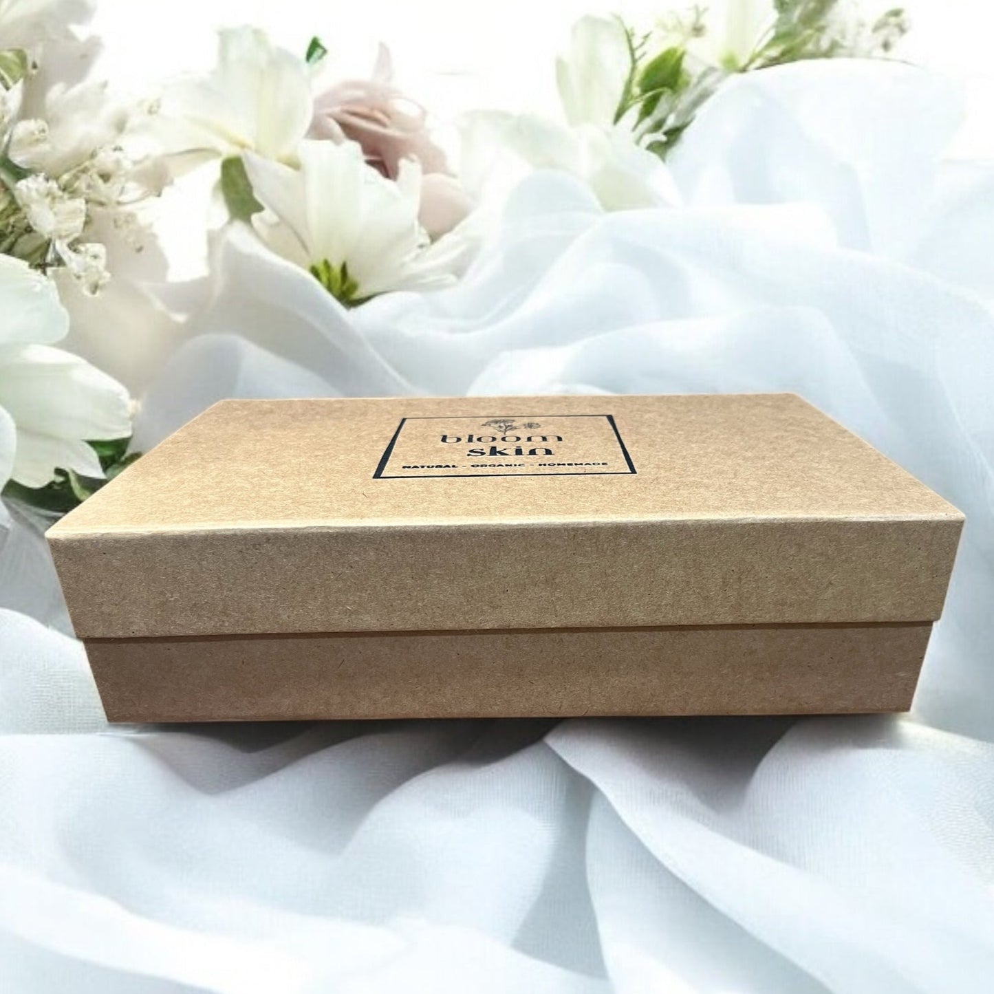 Brown gift box on a white fabric with flowers in the background