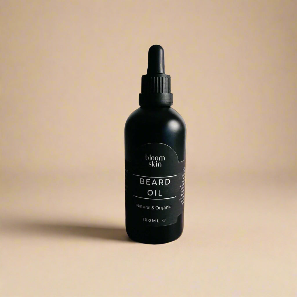 Black bottle of beard oil on a wooden surface with a plant in the background.