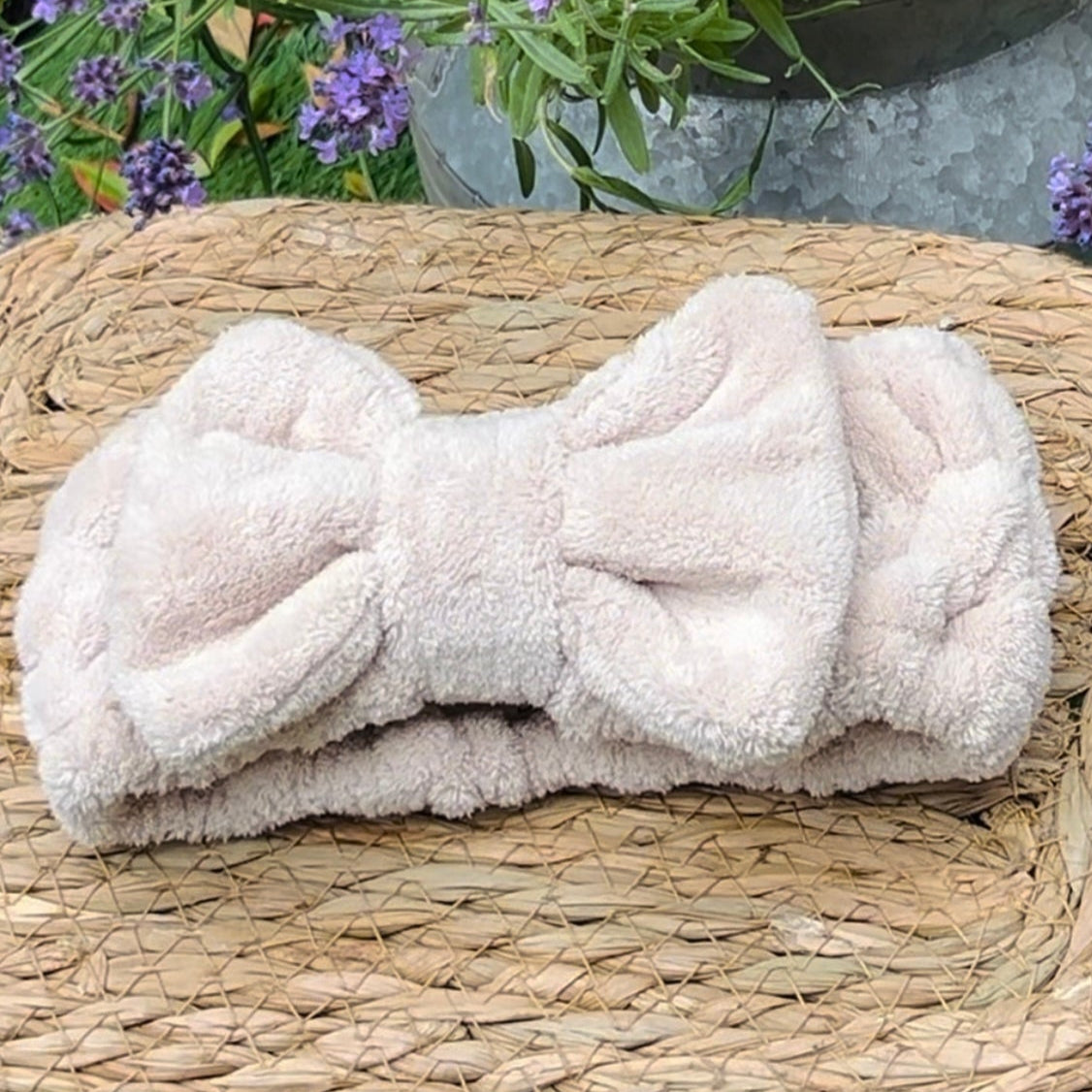 Folded towel with a bow on a woven surface with lavender in the background