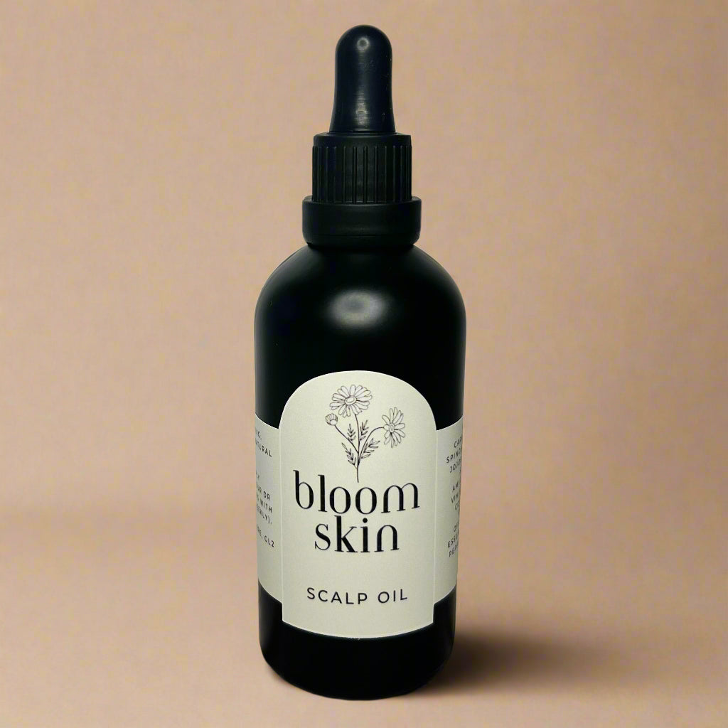 Bottle of bloom skin scalp oil on a wooden surface with a white background