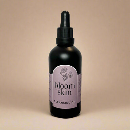 Bottle of 'bloom skin' cleansing oil on a wooden surface with a white background
