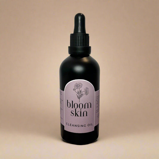 Bottle of 'bloom skin' cleansing oil on a wooden surface with a white background