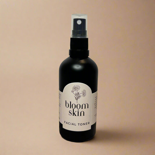 Bottle of 'bloom skin' facial toner on a wooden surface with a white background