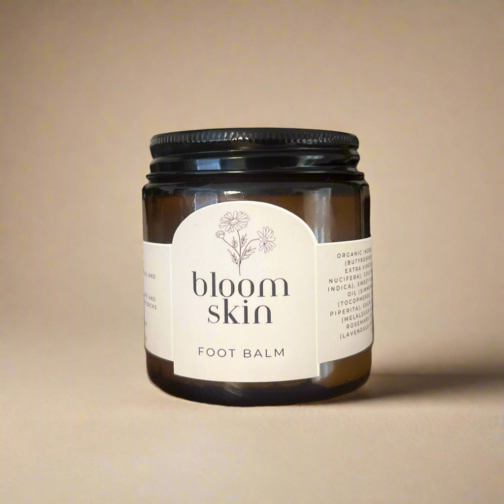 Jars of 'bloom skin' foot balm on a wooden shelf.