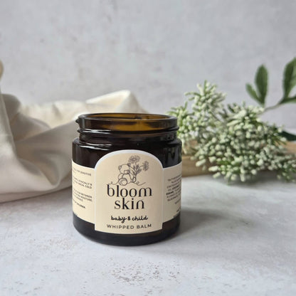Jar of 'bloom skin' whipped balm on a light surface with a neutral background